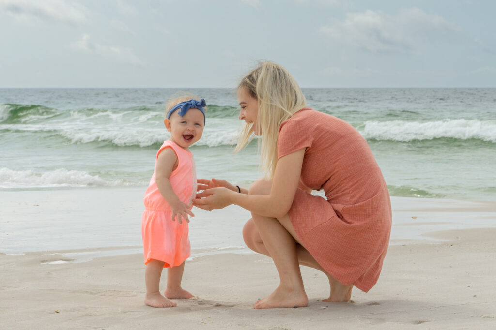 cute mother and daughter laughing on beach