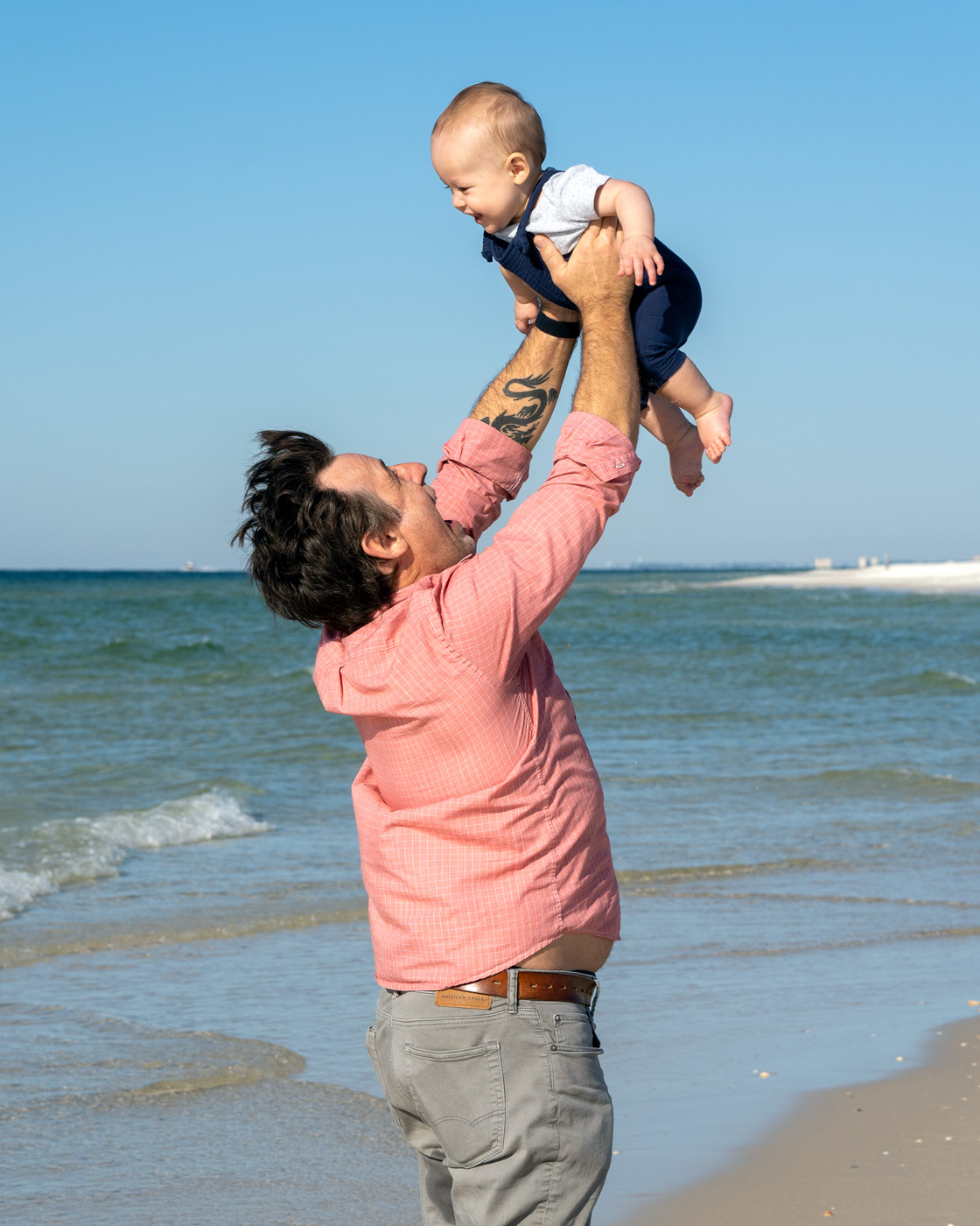 father holding son in air on beach