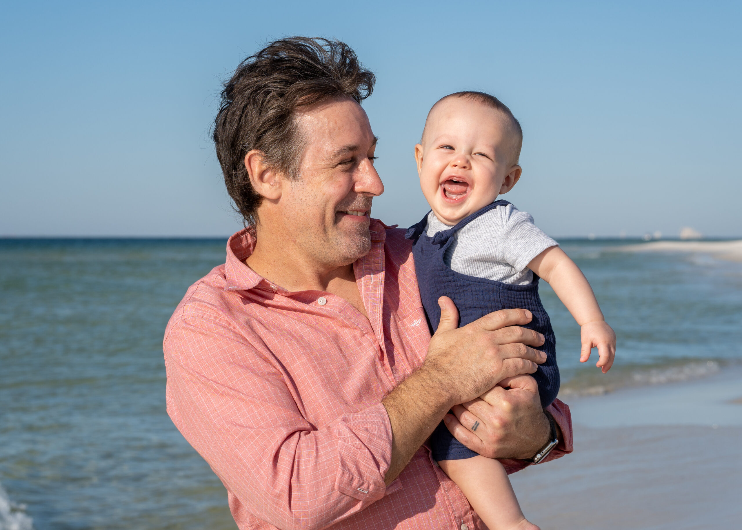 A man holding a baby on the beach