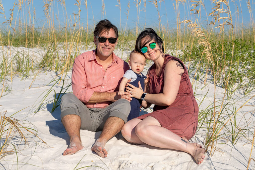 family with infant son on sand dunes