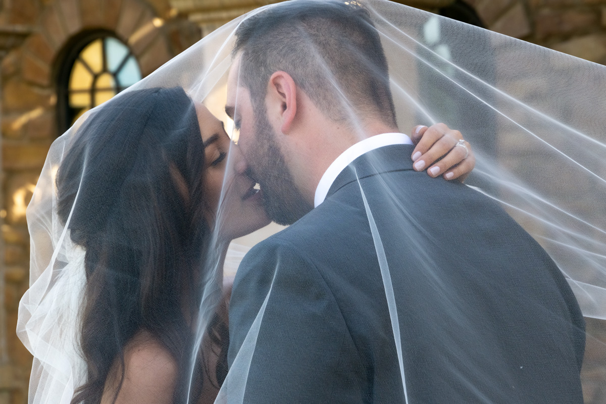 A man and woman kissing under the veil.