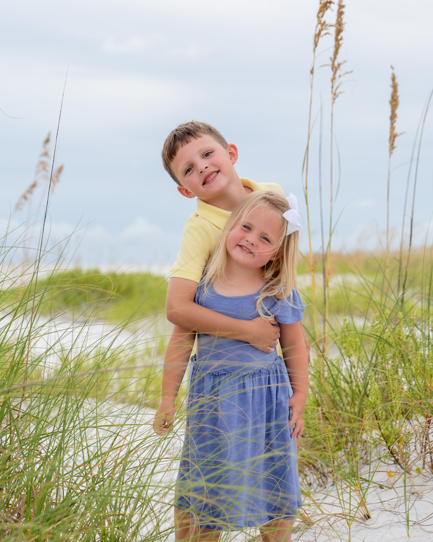 A boy and girl are hugging in the grass.