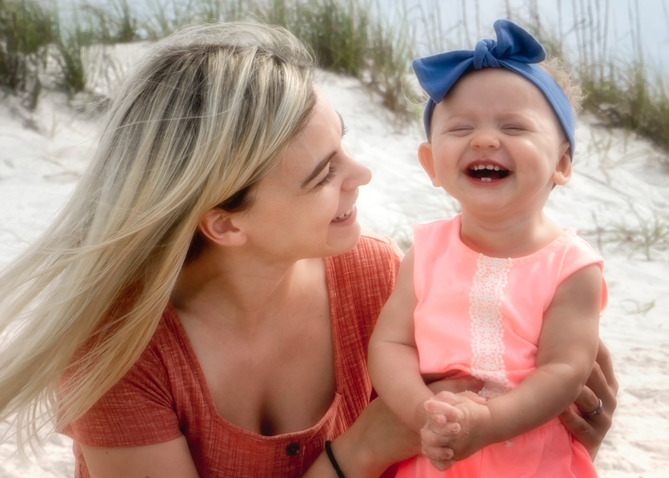 A woman and child laughing on the beach