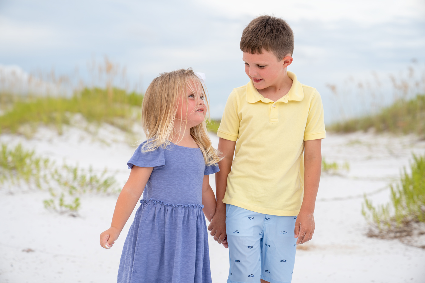 A boy and girl holding hands on the beach