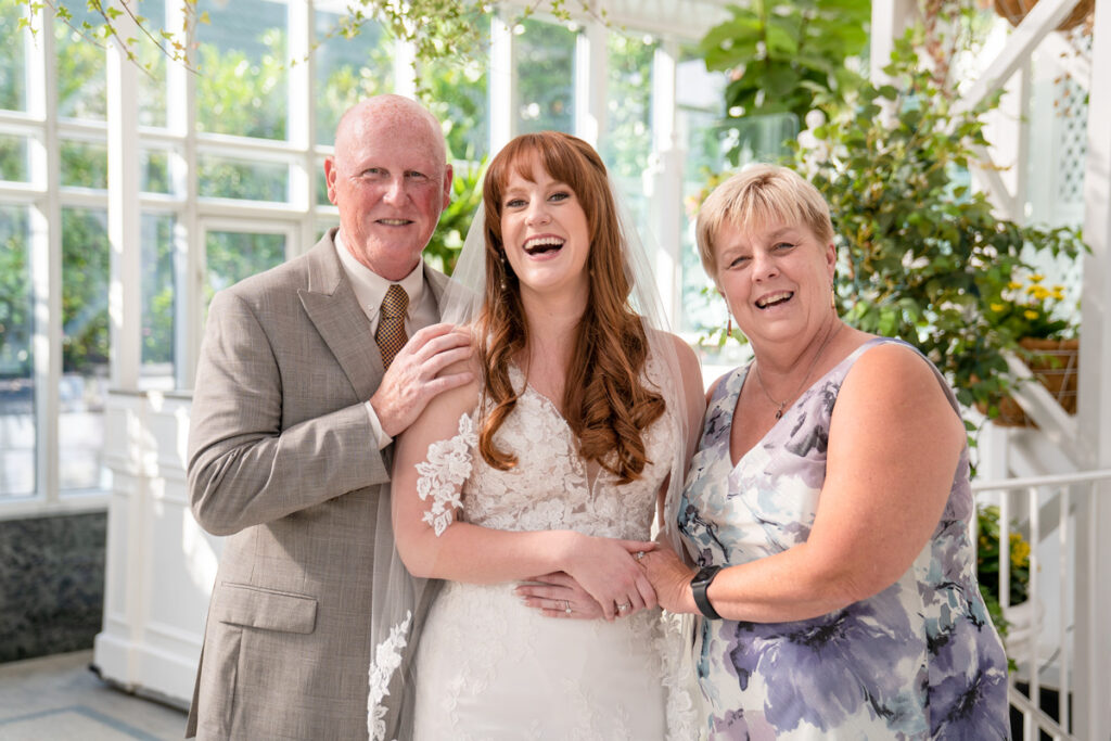 A bride and her parents posing for the camera.