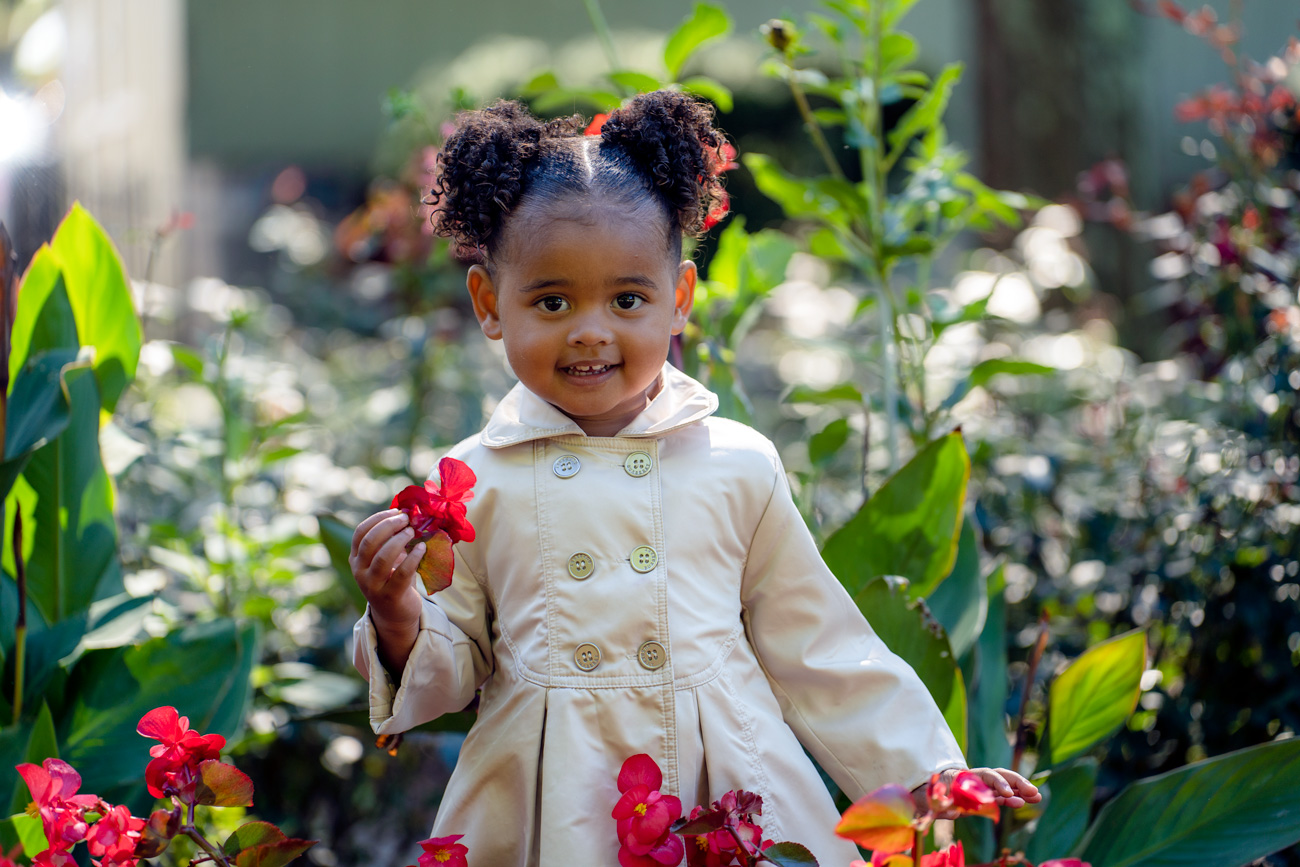 A little girl in a white dress holding flowers.
