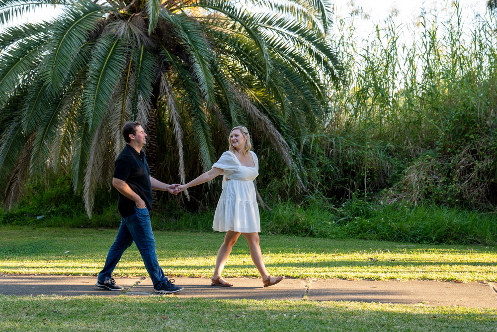 engaged couple walking past palm tree