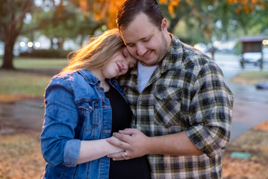 pregnant couple embracing in park