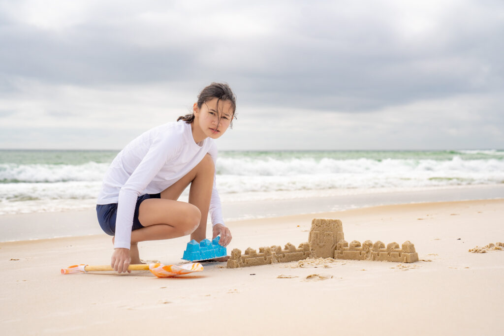 girl building sandcastle on beach