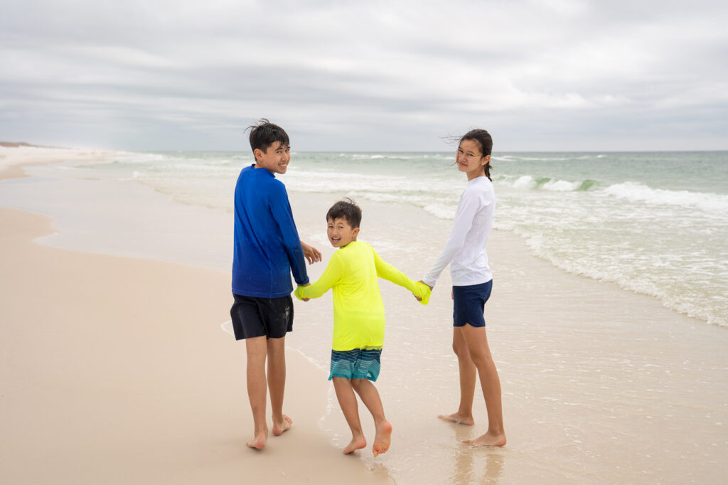siblings holding hands on beach