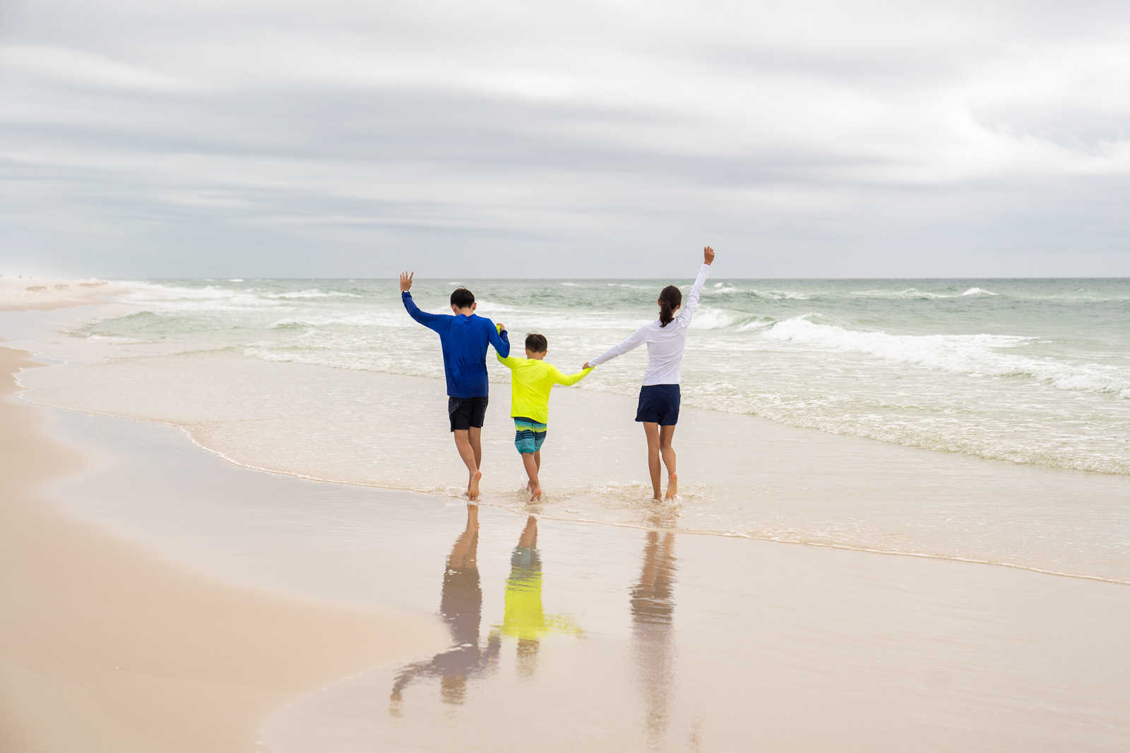 A family of three walking along the beach